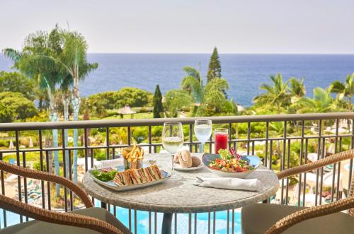 uma mesa com comida e copos de vinho numa varanda em Hotel Porto Mare - PortoBay em Funchal
