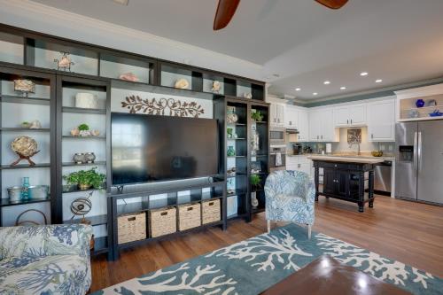 a living room with a large television and a kitchen at Fort Myers Home Near Sanibel Island Causeway in Fort Myers