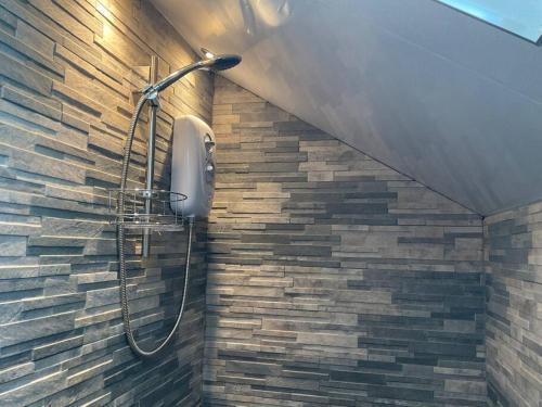 a shower in a bathroom with a stone wall at Kevalsya in Truro