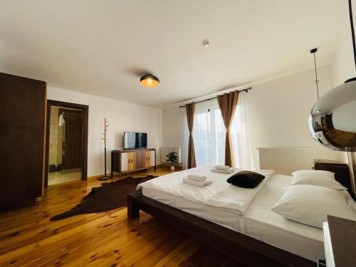 1 dormitorio con 1 cama grande con sábanas y almohadas blancas en PANORAMIC Sus In Deal, en Vişeu de Jos