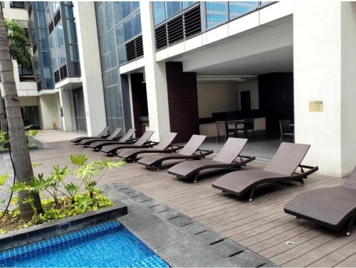 a row of lounge chairs next to a swimming pool at PJ PLACE TO STAY at One Eastwood Tower 1 at Unit 26J in Manila