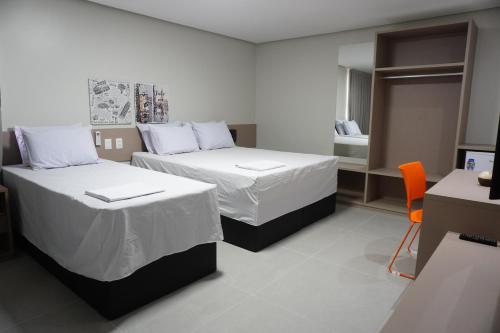 um quarto de hotel com duas camas e uma secretária em Hotel Tupinambá em Santa Inês