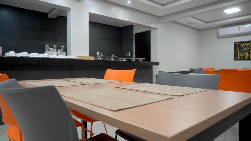 une salle de conférence avec une table et des chaises orange dans l'établissement Hotel Tupinambá, à Santa Inês