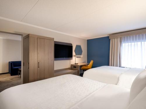 a hotel room with two beds and a flat screen tv at Holiday Inn Express & Suites Greensboro - I-40 atWendover by IHG in Greensboro
