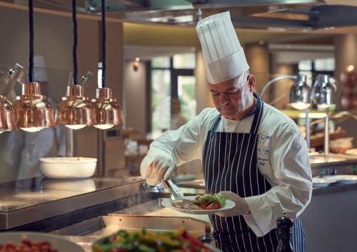 a chef preparing a plate of food in a kitchen at Hotel Porto Mare - PortoBay in Funchal