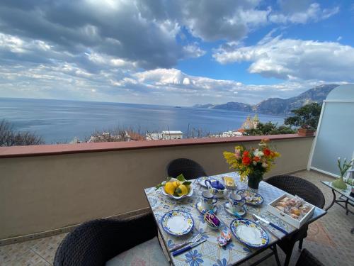 a table on a balcony with a view of the water at Il Profumo dei Fiori in Praiano