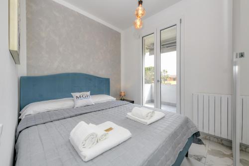een slaapkamer met een blauw en wit bed met handdoeken erop bij MGH Porto Deluxe Apartment in Sirmione