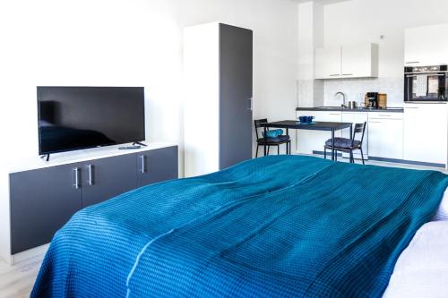 1 Schlafzimmer mit einem blauen Bett und einer Küche in der Unterkunft Ferienwohnungen direkt am Werbellinsee in Joachimsthal