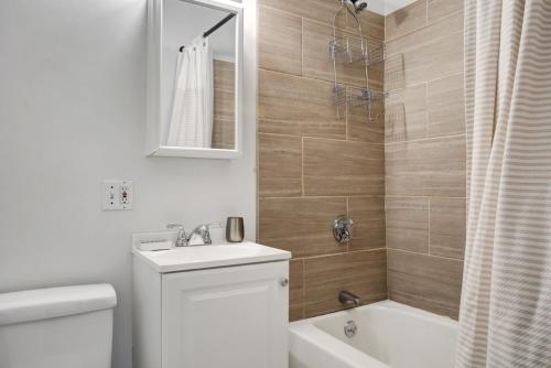 a bathroom with a sink and a toilet and a mirror at Cozy N End 2BR steps from Harborwalk BOS-449 in Boston