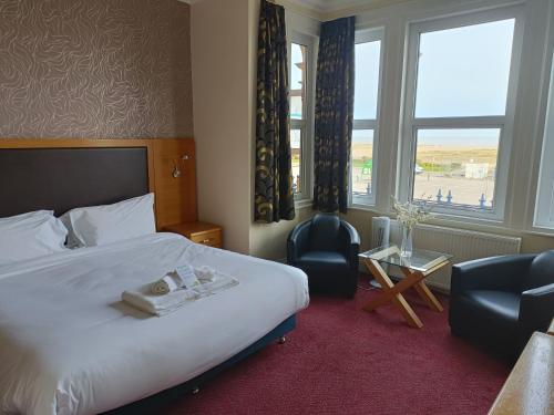 a hotel room with a bed and a chair and a window at Palm Court Hotel in Great Yarmouth