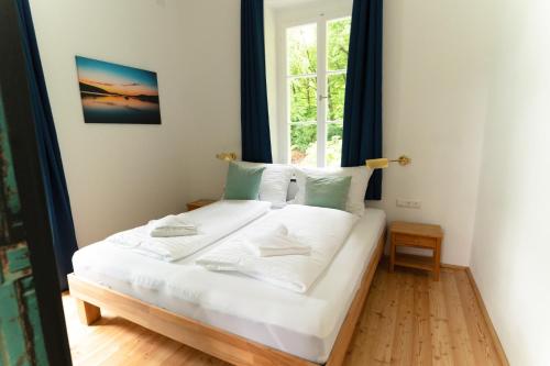 ein weißes Bett in einem Zimmer mit Fenster in der Unterkunft Villa Schwertführer in Velden am Wörthersee