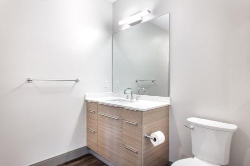 La salle de bains est pourvue de toilettes, d'un lavabo et d'un miroir. dans l'établissement New build Sommerville 2BR w Rooftop WD in unit BOS-364, à Somerville