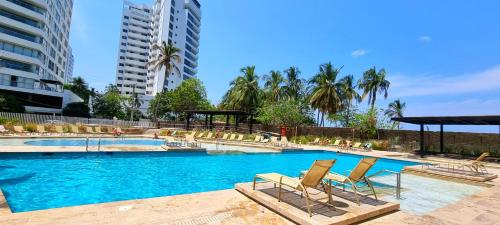 duży basen z krzesłami i palmami w obiekcie Exclusivo Apartamento con vista al Mar - Santa Marta w mieście Puerto de Gaira