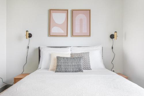 サマービルにあるNew build Sommerville 2BR w Rooftop WD in unit BOS-366の壁に2つのフレームが付いた白いベッドのある寝室