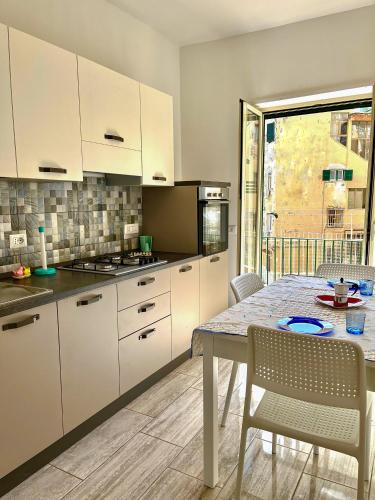 a kitchen with white cabinets and a table with chairs at Il Rifugio Dei Partenopei in Naples
