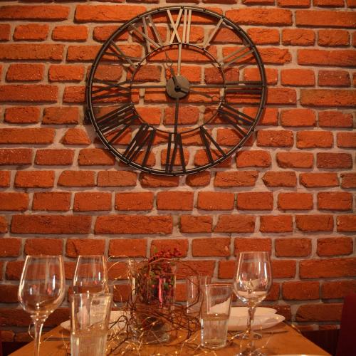 a clock hanging on a brick wall with a table with glasses at Rezidence Valcha in Sušice