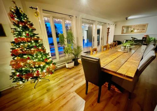 a dining room with a christmas tree and a wooden table at La Couronne boréale in Rivière-Rouge