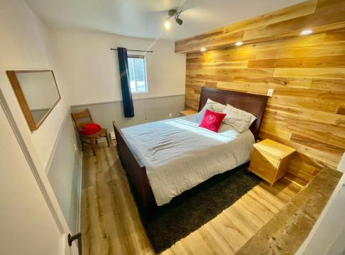1 dormitorio con 1 cama con pared de madera en La Couronne boréale, en Rivière-Rouge