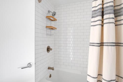 a shower with white tile and a shower curtain at E Cambridge 1BR w WD Gym steps from Train BOS-524 in Boston