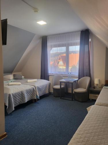 Zimmer mit 2 Betten, einem Tisch und einem Fenster in der Unterkunft Gościniec Pieniński in Kluszkowce
