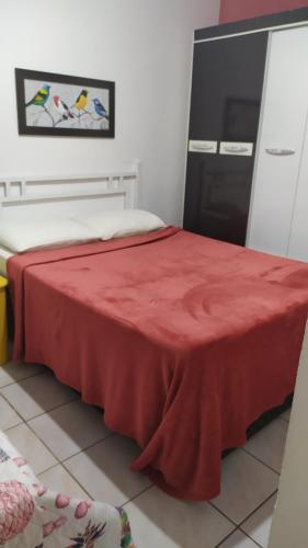 a room with a bed with a red blanket on it at 3 Kitnets in Rio das Ostras