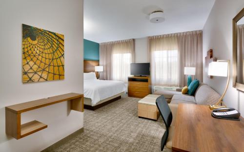 Staybridge Suites - Gainesville I-75, an IHG Hotel في غاينيسفيل: غرفة فندق بسرير ومكتب وغرفة نوم