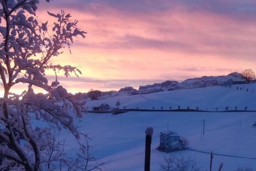 a snowy field with a sunset in the background at Ferienwohnung in Schwellbrunn in Schwellbrunn