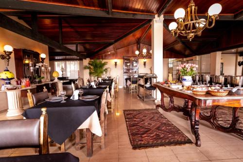 a restaurant with tables and chairs and a chandelier at Hotel Highlander in Gravatá