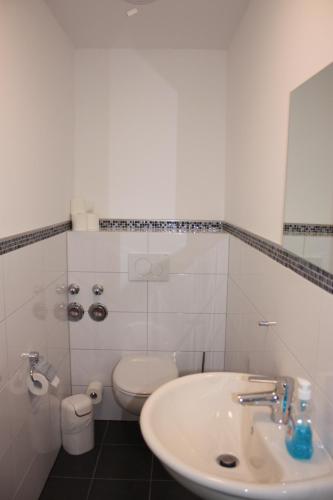 a white bathroom with a sink and a toilet at Ahoi-Gästehaus in Hamburg