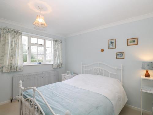 a white bedroom with a bed and a window at Poets Corner in Great Malvern