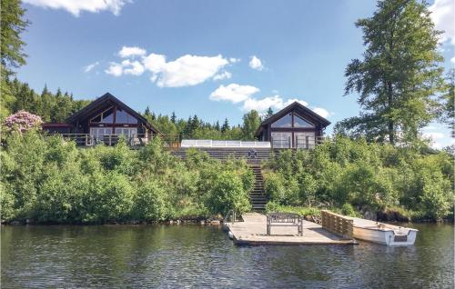 a house on the water with a dock and a boat at Amazing Home In Dalsjöfors With Sauna in Dalsjöfors