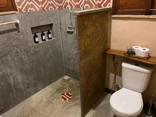 a small bathroom with a toilet and a shower at Quinta dos Laranjais Chalés in Viçosa do Ceará