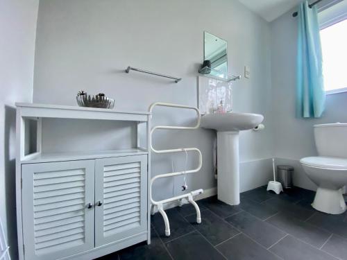 Baño blanco con lavabo y aseo en Charming Spacious 3-bedroom Beach Holiday House, Norfolk en Hemsby
