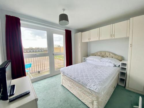 1 dormitorio con cama y ventana grande en Charming Spacious 3-bedroom Beach Holiday House, Norfolk en Hemsby