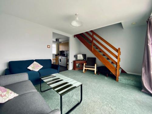 a living room with a couch and a staircase at Charming Spacious 3-bedroom Beach Holiday House, Norfolk in Hemsby