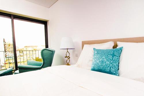 a bedroom with a bed and a chair and a window at Tower View - Apartamento superior no centro de Aveiro in Aveiro