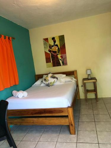 a bedroom with a bed and a painting on the wall at Sunshine Hotel Little Corn Island in Little Corn Island