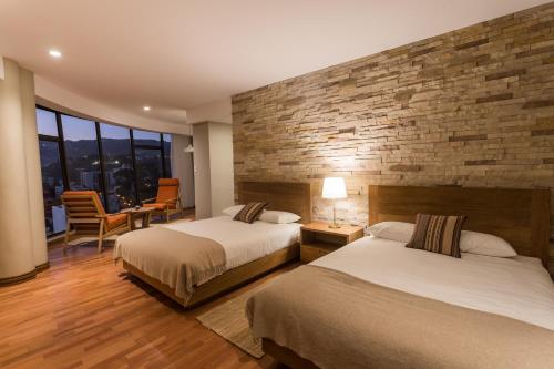 a hotel room with two beds and a brick wall at Hotel Boutique Rosario Sur in La Paz
