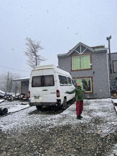 Ein Mann steht neben einem Van im Schnee. in der Unterkunft Caballo de Fuego in Ushuaia