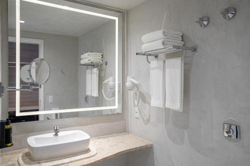 a white bathroom with a sink and a mirror at Sooz Hotel Collection in Sao Paulo