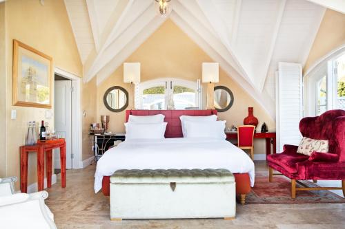 a bedroom with a large white bed and two red chairs at Birkenhead House in Hermanus