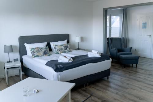 a bedroom with a large bed and a chair at Hotel-Restaurant Nordlicht in Kappeln