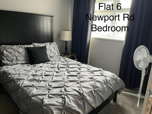 a bedroom with a bed with a grey comforter and a fan at Stafford apartments in Stafford