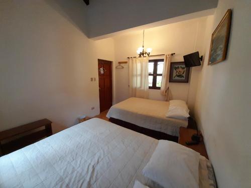 a hotel room with two beds and a window at Hotel y Jardines Casa Búho in Antigua Guatemala
