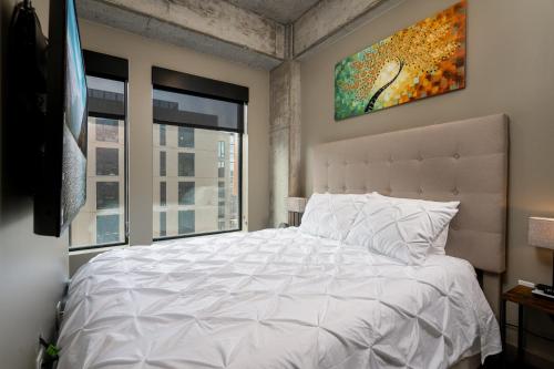 een slaapkamer met een wit bed en een schilderij aan de muur bij Sable 44 - One Bedroom in Minneapolis