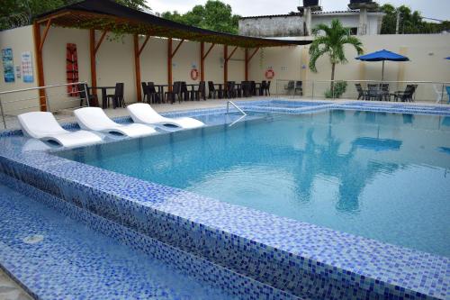 una gran piscina con sillas y mesas blancas en Cabañas Covemar de lujo en Coveñas