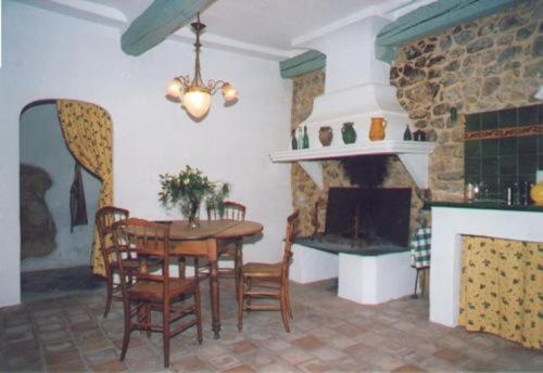 a dining room with a table and chairs and a fireplace at La Placette - votre maison en pierres authentique in Bizanet