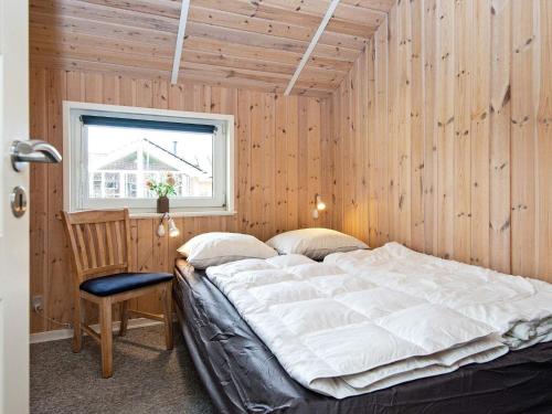 1 dormitorio con 1 cama, 1 silla y 1 ventana en Holiday home Oksbøl LXXXII, en Oksbøl