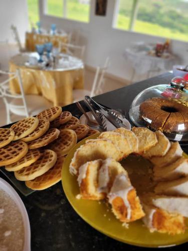 een tafel met een bord vol eten, zoals wafels en taarten bij Pousada Sal da Terra in Carrancas