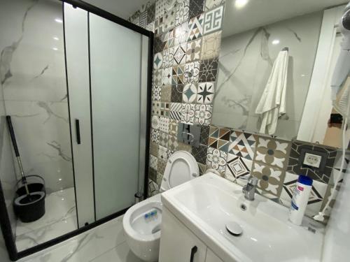 La salle de bains est pourvue d'un lavabo blanc et de toilettes. dans l'établissement Antalya lara suite more, à Antalya